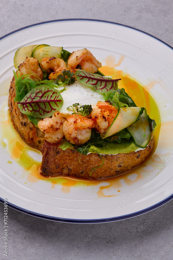 Toast with shrimp, prawns, avocado and poached egg on grey background Toast with shrimp, prawns, avocado and poached egg on grey background