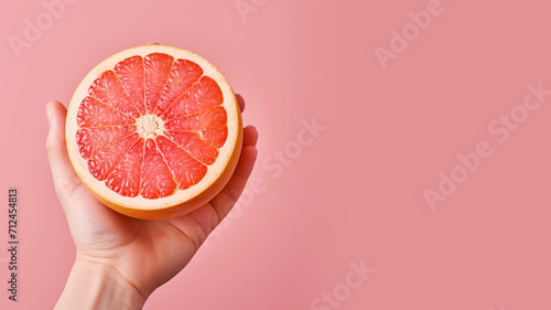 Hand holding sliced grapefruit isolated on pastel background photo