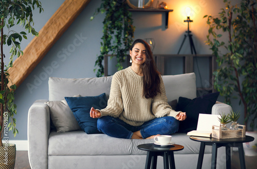 Cute smiling woman is learing yoga at home photo