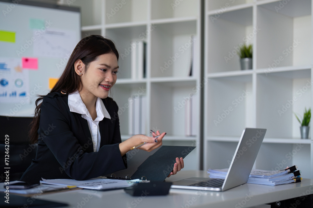 Beautiful asian businesswoman woman using calculator and laptop for doing finance on an office desk, tax, report, accounting, statistics, and analysis research concept Beautiful asian businesswoman woman using calculator and laptop for doing finance on an office desk, tax, report, accounting, statistics, and analysis research concept