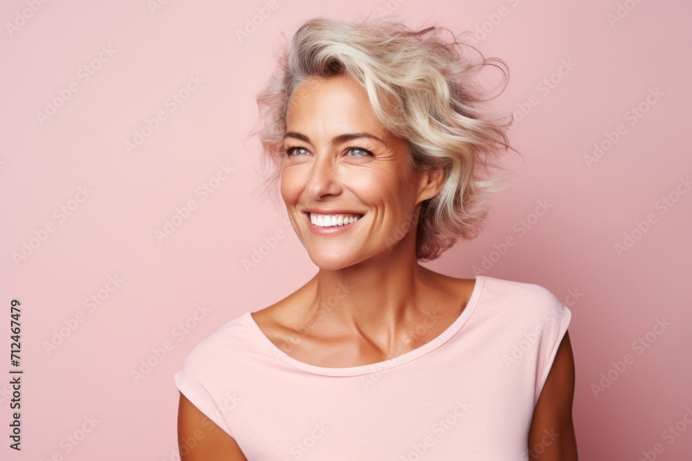 Portrait of a beautiful middle aged woman with blonde hair on a pink background Portrait of a beautiful middle aged woman with blonde hair on a pink background