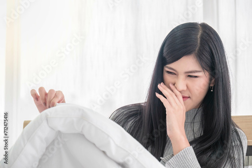 Beautiful woman stinky blanket and pillow breath fingers on nose poses. asian girl lovely sitting and sleep smelling to smmelly pillow on the bed stench stink foul stench in housework.