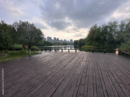 A wooden platform in Yanghu Wetland Park, Hunan, Changsha, China. Trees, lake, building. photo