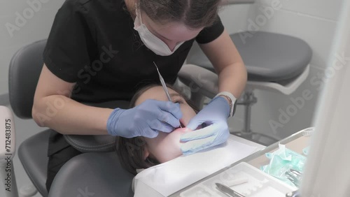 A pediatric dentist examines the oral cavity and baby teeth of a child's patient using a dental explorer. Preventive dental examination of teeth and gums to prevent caries and periodontal diseases. photo