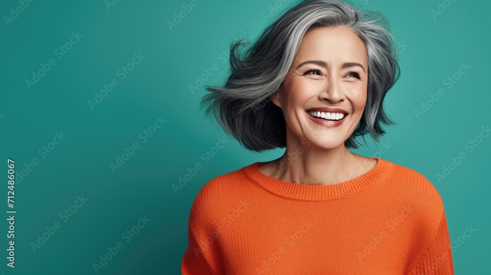 Portrait of an attractive cheerful gray-haired woman having fun, isolated on a bright turquoise background with a camera Portrait of an attractive cheerful gray-haired woman having fun, isolated on a bright turquoise background with a camera