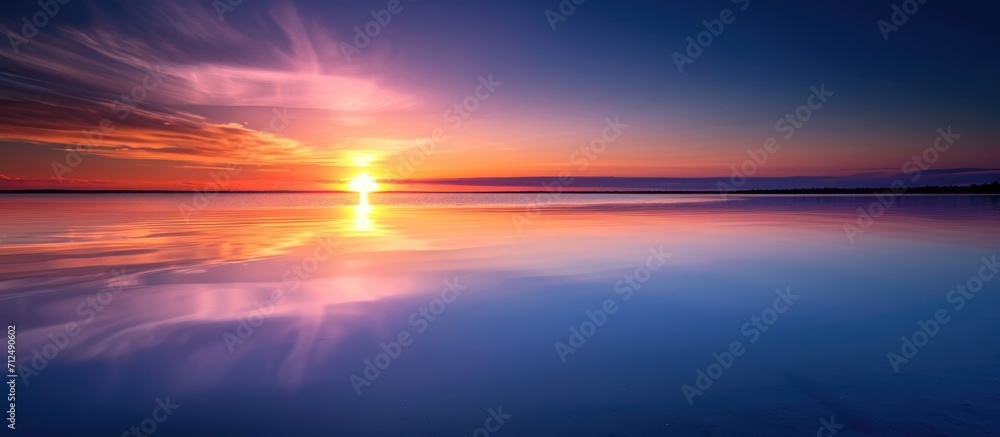Obraz premium Sunrise or sunset reflecting on still water fading into the distance.