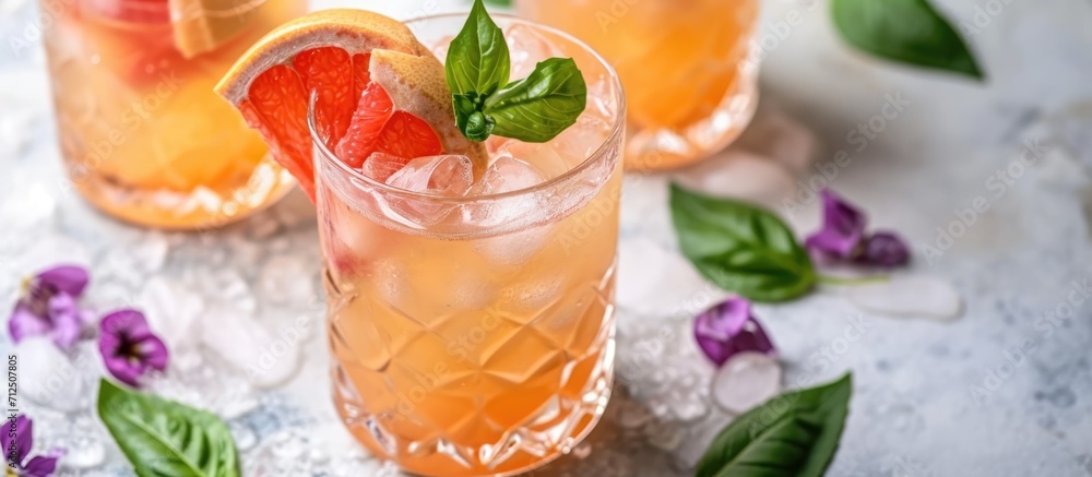 Refreshing summer cocktail with grapefruit and violet red basil, served in a glass jar on a light concrete surface. Refreshing summer cocktail with grapefruit and violet red basil, served in a glass jar on a light concrete surface.