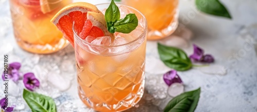 Refreshing summer cocktail with grapefruit and violet red basil, served in a glass jar on a light concrete surface.