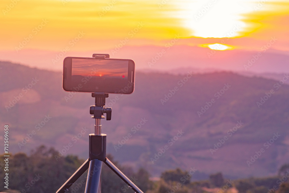 A smartphone is recording the sun setting over a mountain range. A smartphone is recording the sun setting over a mountain range.