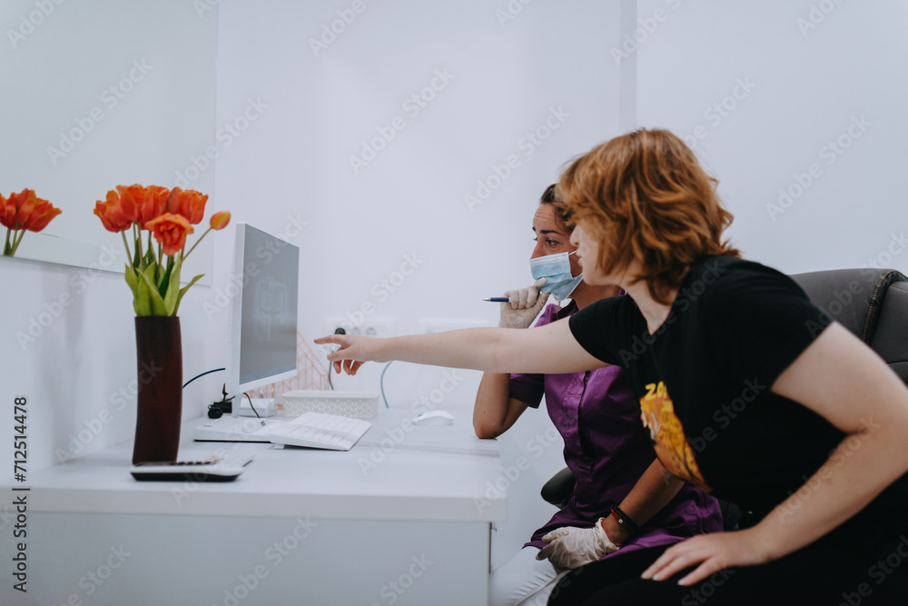 In a modern dental office, a dentist and a young patient engage in a collaborative consultation, exploring new tooth shades and discussing treatment options using a computer In a modern dental office, a dentist and a young patient engage in a collaborative consultation, exploring new tooth shades and discussing treatment options using a computer