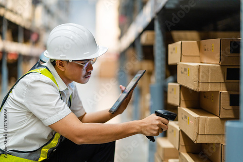Warehouse employee scans barcodes on boxes in the warehouse. Male worker, warehouse with goods, distribution, logistics. photo