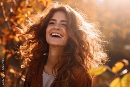 Portrait of a happy relaxed woman enjoying autumn with dry fallen leaves and sunlight in the background