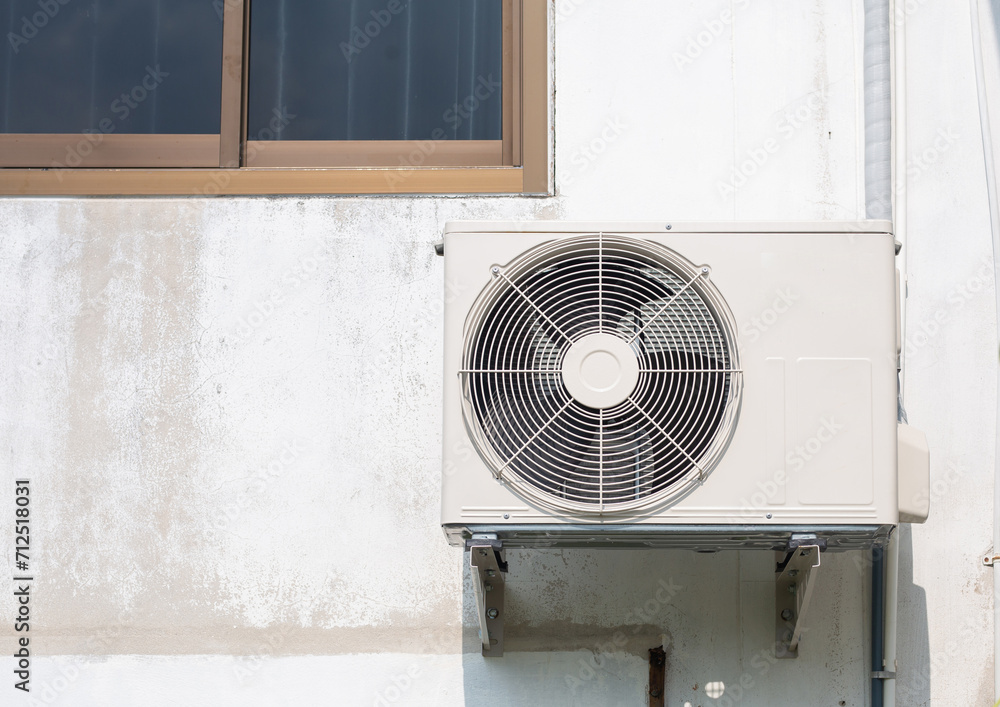 The air conditioner is installed outside the building near a glass window. The air conditioner is installed outside the building near a glass window.