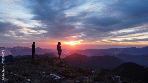 People standing at sunrise in the mountains