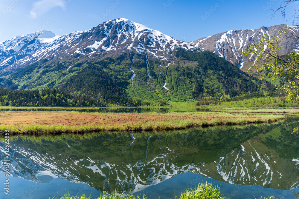 Fototapeta premium Tern Lake along Seward Highway on Kenai Peninsula in Alaska. At junction with Sterling Highway in Chugach National Forest. Mountain landscape perfectly reflected in mirror still alpine lake.