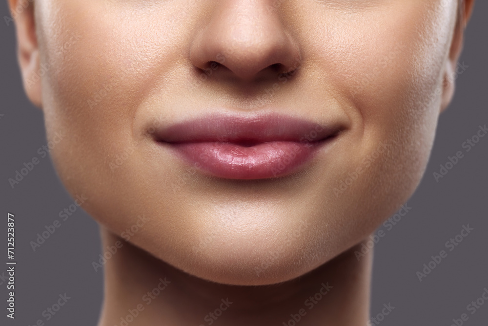Beautiful female lips. Close-up of person's lower face featuring well-defined, plump lips with subtle natural gloss. Concept of Lip care, moisturizing and plumping cosmetic products for lips. Ad Beautiful female lips. Close-up of person's lower face featuring well-defined, plump lips with subtle natural gloss. Concept of Lip care, moisturizing and plumping cosmetic products for lips. Ad