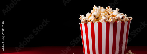 popcorn in a background, good popcorn scattering from a red striped carton box on a dark background