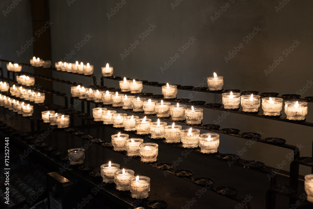 Brennende Kerzen aufgereiht als Opferkerzen auf Metallgestell in einer Kirche