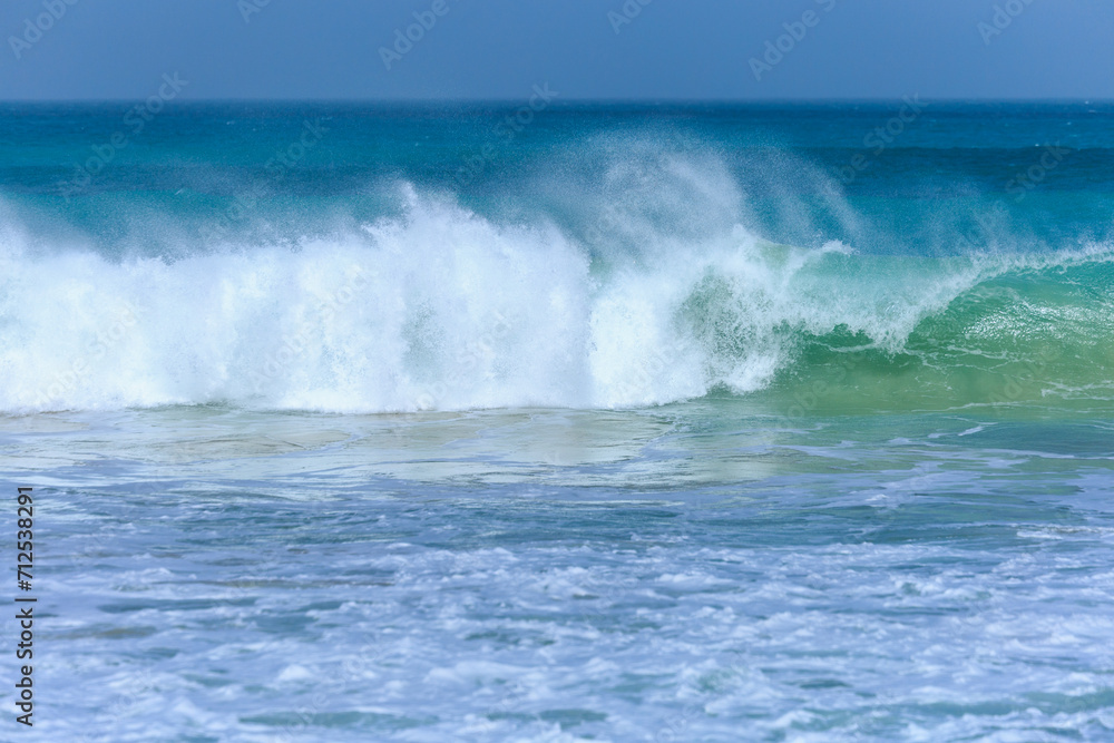 A large wave with turquoise water and white foam approaches on a windy day at Boa Vista's beach, Cape Verde.