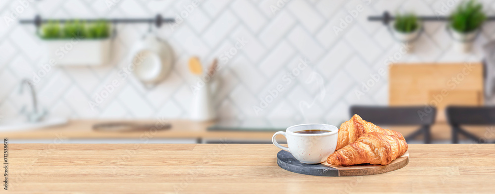 Croissant and coffee on wooden table top in modern kitchen, breakfast concept, Long banner format. copy space for text