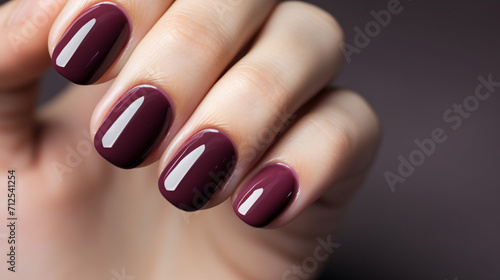 Woman hand with burgundy color nail polish on her fingernails. Burgundy nail manicure with gel polish at luxury beauty salon. Nail art and design. Female hand model. French manicure.