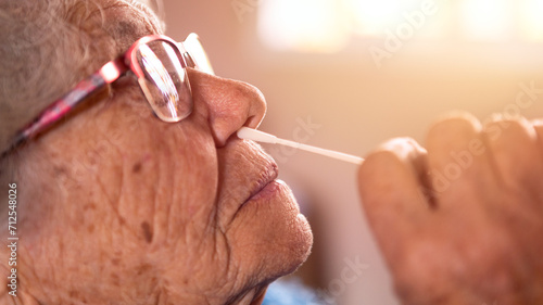 Portrait of old woman taking a self swabbing home tests Covid19 with antigen kit photo