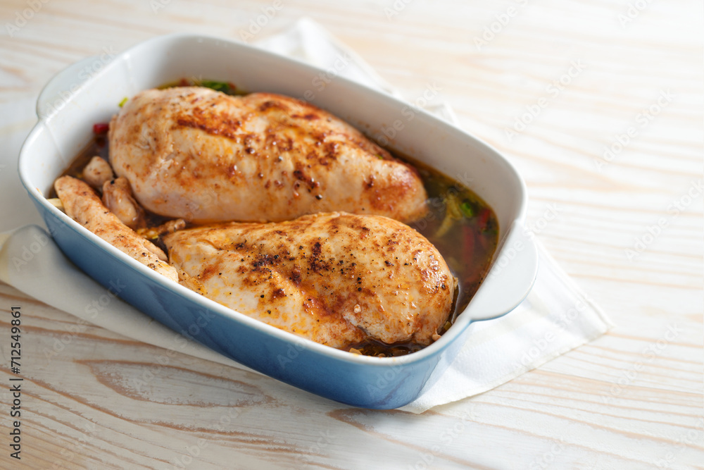 Chicken breast fillet, seasoned with paprika, pepper and salt on a bed of vegetables and broth in a casserole, prepared for braising in the oven, cooking at home, copy space Chicken breast fillet, seasoned with paprika, pepper and salt on a bed of vegetables and broth in a casserole, prepared for braising in the oven, cooking at home, copy space