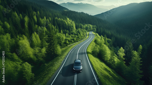 EV (Electric Vehicle) electric car is driving on a winding road that runs through a verdant forest and mountains © Александр Марченко