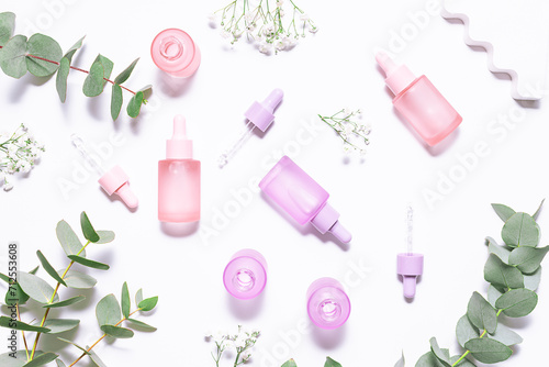 Set of organic eco skin care products in colorful unbranded containers , beautiful flowers and eucalyptus leaves on white background top view. Cosmetic branding concept.