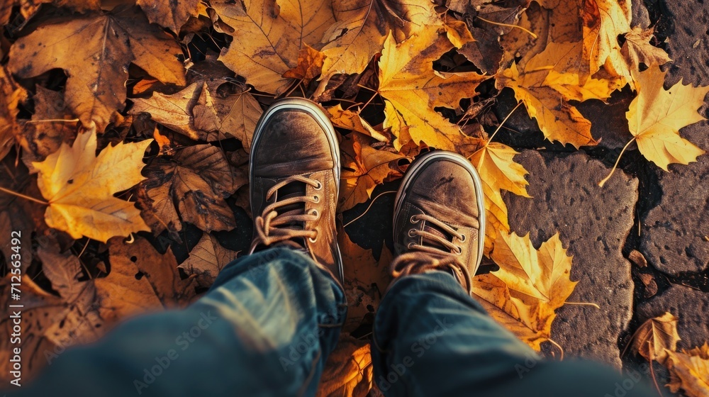a person's feet in a pair of brown shoes standing on a leaf covered ground with yellow leaves on the ground. a person's feet in a pair of brown shoes standing on a leaf covered ground with yellow leaves on the ground.