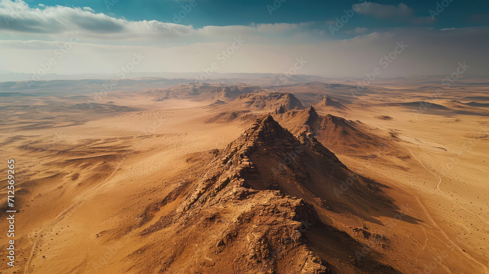 Aerial view of a majestic mountain rising from the vast expanse of a desert landscape