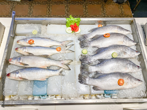 Fresh frozen barramundi and fourfinger threadfin fish with ice sold at a modern fish market. Fish caught by fishermen. Concept for whole healthy food, nutrition, omega-3, animal protein, seafood. photo