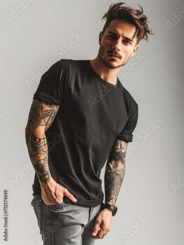 Tattooed man wearing black t-shirt short sleeve and grey jeans isolated on plain background