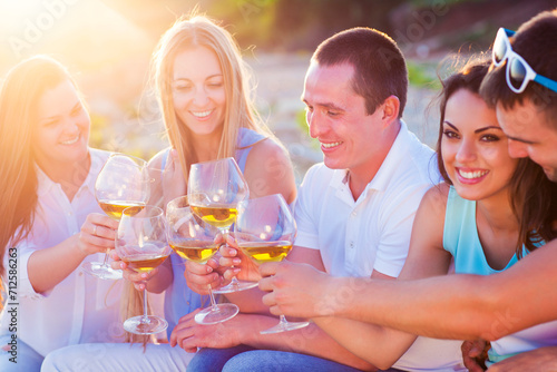 People holding glasses of white wine making a toast at the beach