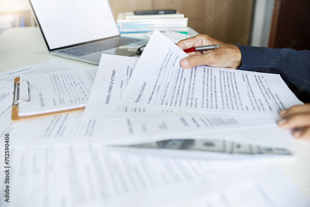 Businessman or lawyer working on desk reading and reviewing business contract and power of attorney before making a business contract and recive dollars for commission Businessman or lawyer working on desk reading and reviewing business contract and power of attorney before making a business contract and recive dollars for commission