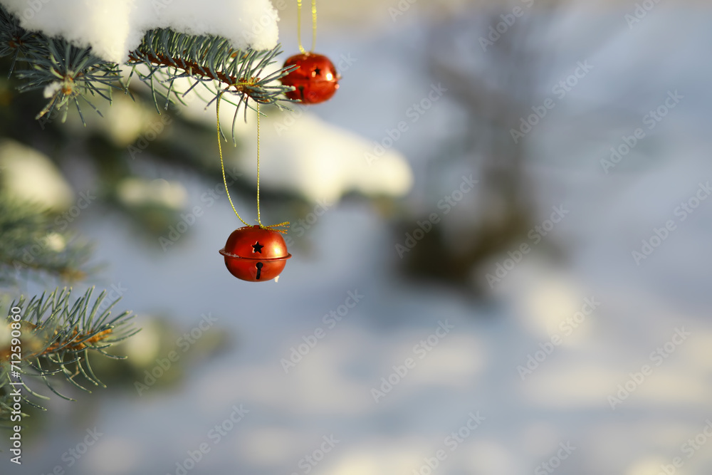 Red Christmas bell hangs on a snow-covered branch of a Christmas tree against a festive background of white snow. New Year, greeting and holiday card, banner. Red Christmas bell hangs on a snow-covered branch of a Christmas tree against a festive background of white snow. New Year, greeting and holiday card, banner.