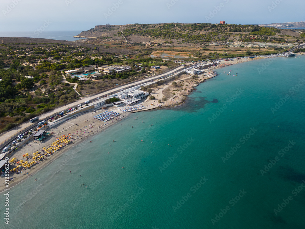 Aerial view of beautiful Ghadira Bay, Mellieha, Malta with turquoise sea and sandy beach. Coastal road towards Red tower and Gozo ferry terminal. 