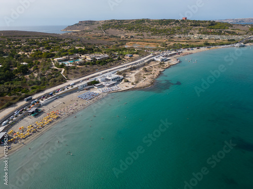 Aerial view of beautiful Ghadira Bay, Mellieha, Malta with turquoise sea and sandy beach. Coastal road towards Red tower and Gozo ferry terminal. 