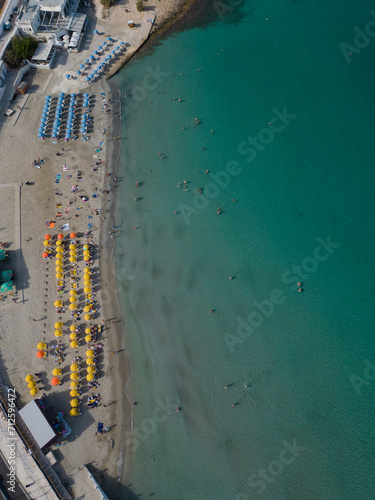 Yellow and blue lines of sunshades on a sandy beach by clear turquoise sea. Aerial view on Ghadira Bay Mellieha top down. Summer in Malta. © Ssisabal