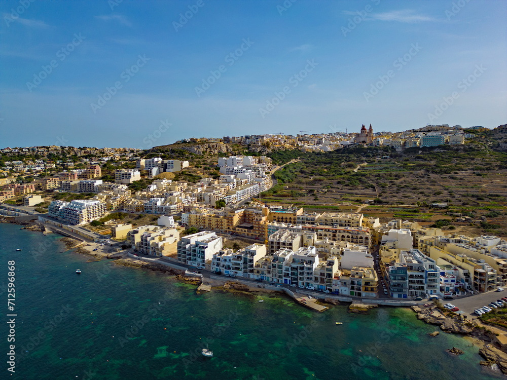 Mellieha beach town in Malta with Church on the top of the hill aerial view. Mellieha is popular tourist beach destination.
