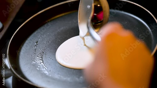 Closeup of making steaming hot crepe layer on a cast iron pan. A thin pancake made with rice flour dough and condensed milk stuffing. Thin batter being spread and cooked for making 'Pithe' and 'dosa' photo