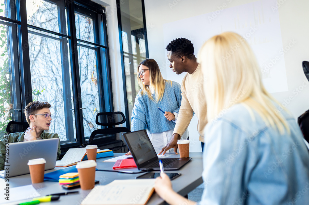 Diverse group of young business people working on new project together in office. Diverse group of young business people working on new project together in office.