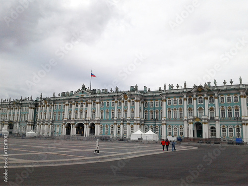 Hermitage Museum. People go to the museum. Flag of Russia on the building. Cloudy day in St. Petersburg.