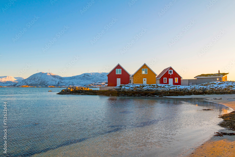 Traditional red and yellow wooden norwegian cabins with ground on the roof. Tromso, Norway