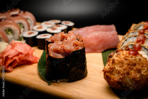 Focus on two gunkan with tuna, rest types of sushi philadelphia, nigiri, maki on blurred background