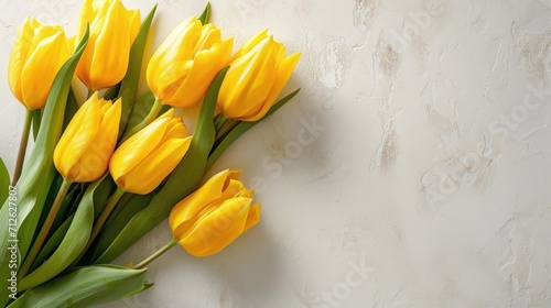a bouquet of yellow tulips lies on the right on a simple light background, copy space