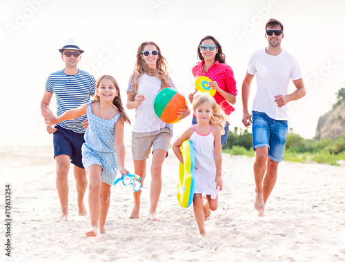 Multiracial group of friends with children running at the beach