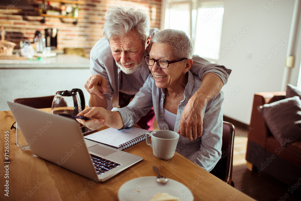 Smiling senior couple using laptop together at home Smiling senior couple using laptop together at home