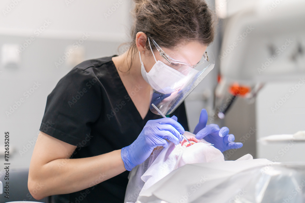 The dentist examines the patient's mouth and teeth using a dental