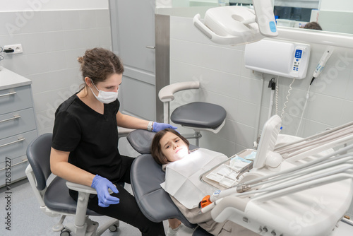 A pediatric dentist examines an anxious child who has come to an appointment for the first time. Medical examination of a child at a pediatric dentist. Prevention of diseases of baby teeth in children